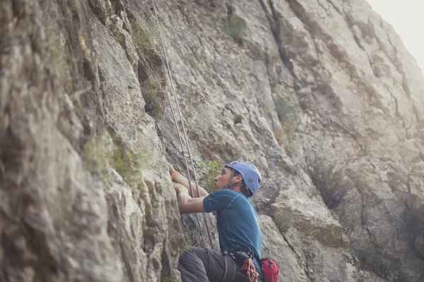 Profesyonel erkek dağcı bir kaya tırmanışı.