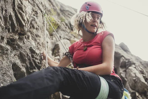 Female alpinist climbing a rock.