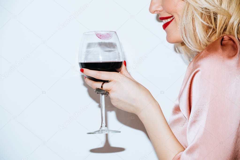 Cropped smiling blonde woman holding a glass of red wine.