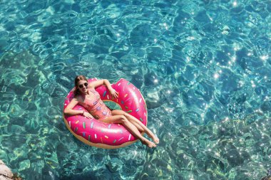 Güzel kadın Akdeniz ve zevk üzerinde kayan halka yatan güneşlenmek.