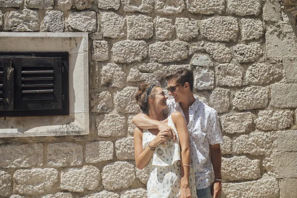 古い地中海の町で石の壁のそばに立って愛の若いカップルの肖像画 — ストック写真