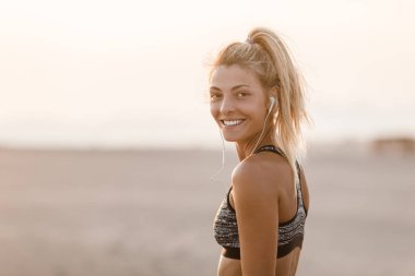 Sahilde duran ve kameraya bakarak oldukça beyaz gülümseyen sporcumuz runner.