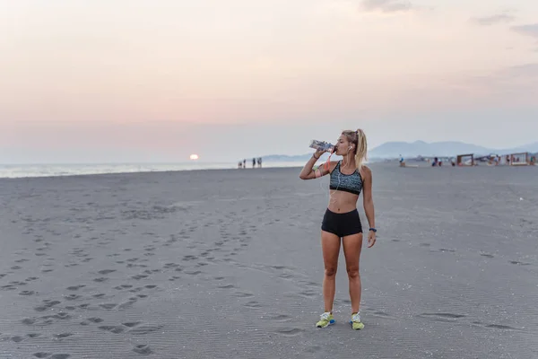 Hübsche Sportlerin Steht Sandstrand Und Trinkt Wasser — Stockfoto