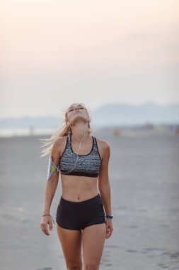 Güzel sporcumuz kumlu plaj ve stratching boynunu ayakta.