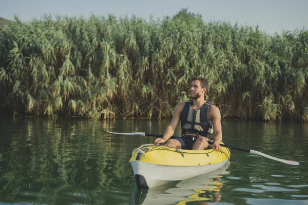 英俊的白人微笑的人皮划艇皮艇享受独木舟在河上 — 图库照片