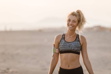 Sahilde duran ve kameraya bakarak oldukça beyaz gülümseyen sporcumuz runner.