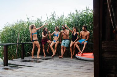 Grup gülümseyen insanların güvertede ayakta ve yaz aylarında birlikte zevk mayo.