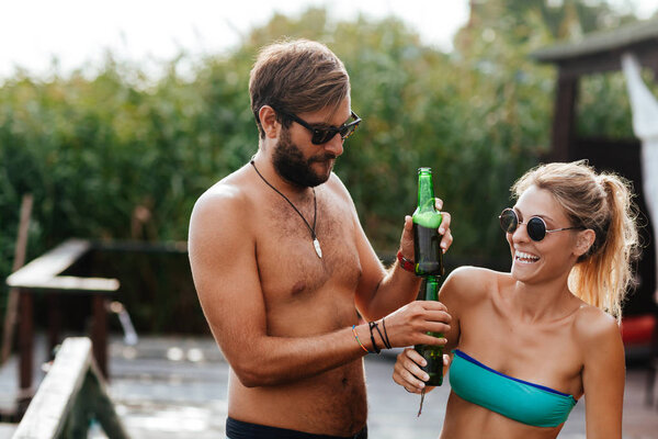 Boyfriend and girlfriend drinking beer and enjoying summertime on seaside.