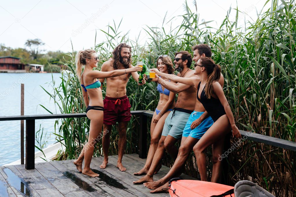 Group of smiling people in swimwear standing on deck and enjoying summertime together.