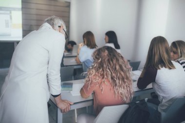 Orta yaşlı bir kadın öğretmen kız öğrenci bir ders ile yardımcı.