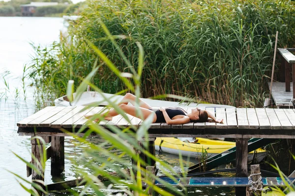 川でデッキの上に横たわると 夏を楽しむ水着で美しい女性 — ストック写真