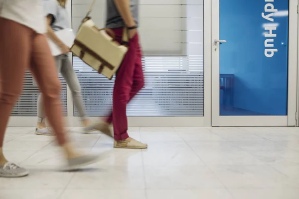 Group of unrecognisable blurred students walking at high school hallway.