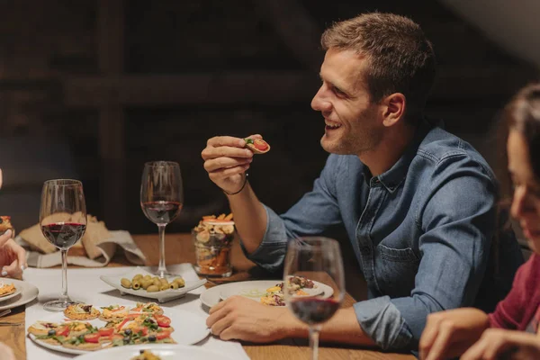 ハンサムな若い白人男のディナー パーティーで食べると 幸せそうに見えて — ストック写真