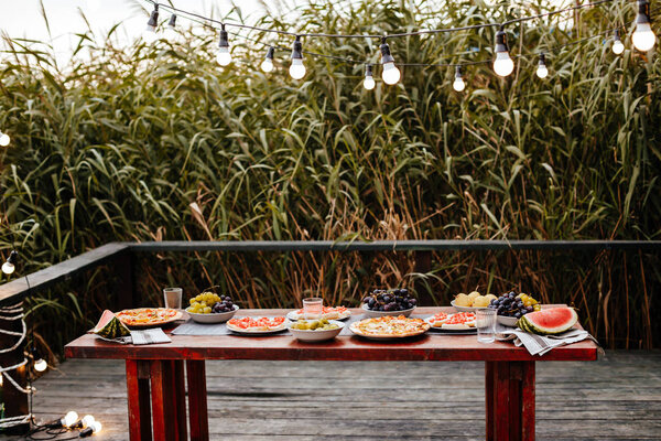 Food served on wooden table for outdoor dinner party.