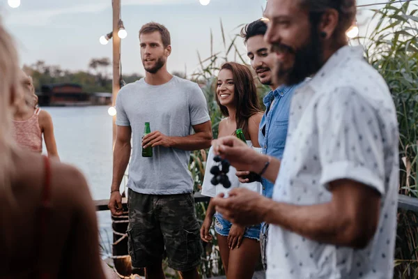 Group of young people having outdoor dinner party by the river.