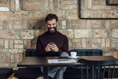 Bir kahve dükkanında bir cep telefonu kullanarak beyaz yakışıklı genç.