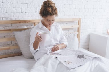 Gazeteler okuma ve yatakta kahve içme oldukça beyaz kadın
