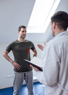 Genç yakışıklı beyaz hastaya onun doktor fizik tedavi tavsiye almak.