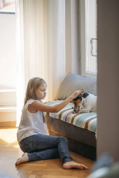 自宅に彼女の犬のペットを抱きしめるかなりブロンドの女の子 — ストック写真
