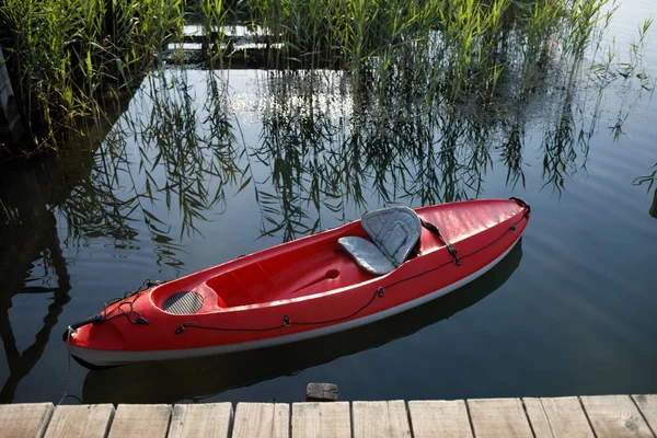 Kayak floating in the water tied to a wooden dock.