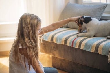 Güzel sarışın kız onun köpek ile evde beslenen hayvan evde oynarken.