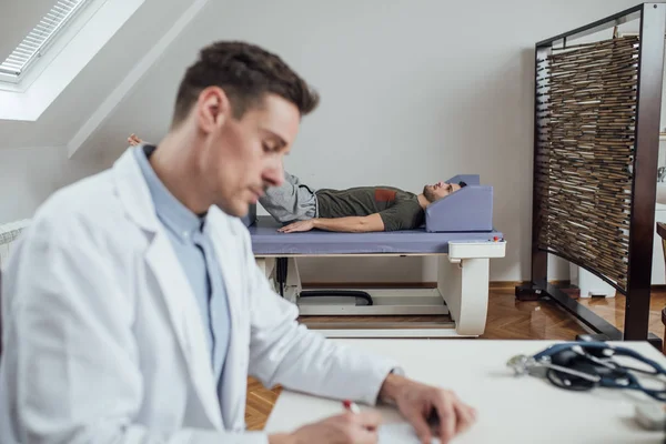 Jonge Kaukasische Medisch Technicus Schrijven Van Diagnose Terwijl Zijn Patiënt — Stockfoto