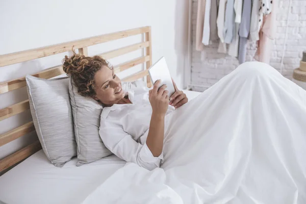 Vrij Lachende Kaukasische Vrouw Liggend Haar Bed Lezen Haar Tablet — Stockfoto