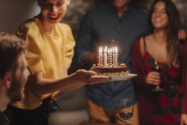 Doğum günü pastası partide tutan güzel gülümseyen genç kadın.