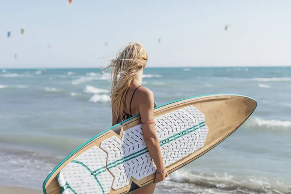 美丽的年轻白种女孩站在沙滩上与冲浪板的背面视图 — 图库照片