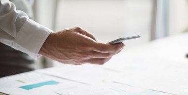 Eller genç işadamı modern ofis alanı notlar ve grafiklerin onun cep telefonu ile fotoğraf çekme.