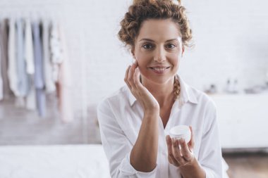 Bir cilt kremi yüzüne sırasında her sabah rutin uygulama bir çok gülümseyen Genç beyaz bir kadın portresi.