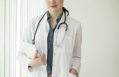 Tablet tutarak ve hastanede ayakta unrecognisable kadın doktor.