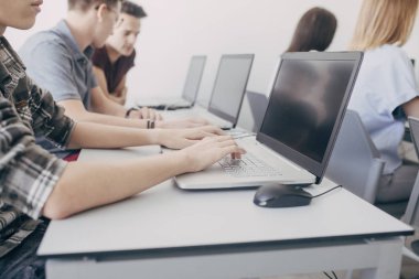 Grup modern sınıf oturma ve dizüstü bilgisayarlarda yazmaya lise öğrenci.