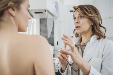 Oldukça kafkas kadın doktor hastasını ile meme muayenede konuşuyor.