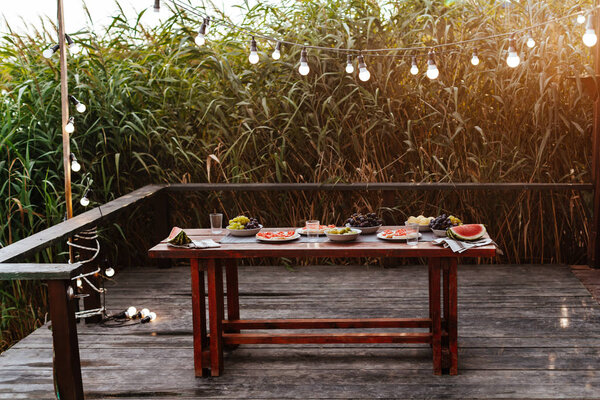 Food served on wooden table for outdoor dinner party.