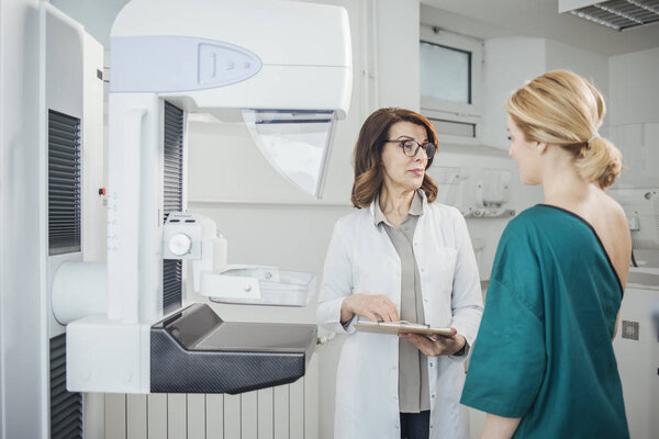 Woman oncologist talking with her patient on mammography examination.