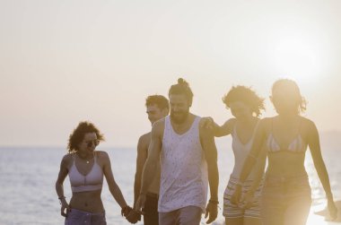 Kumlu sahilde yürüyüş ve mutlu görünüyordu kadın ve genç erkek grup.