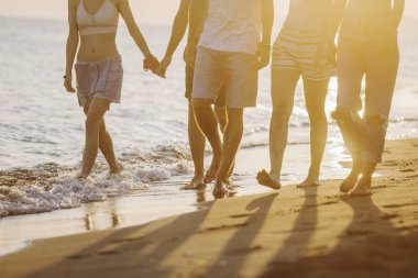 Kumlu sahilde yürüyüş ve mutlu görünüyordu kadın ve genç erkek grup.