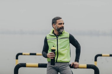 Yakışıklı orta yaşlı beyaz adam atlet bir alarak bir şişe tutan bir ara.