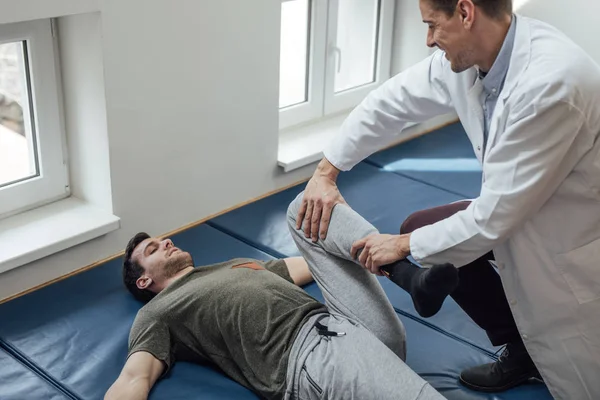 Jovem Bonito Homem Caucasiano Esticando Perna Com Seu Médico Ajudando — Fotografia de Stock