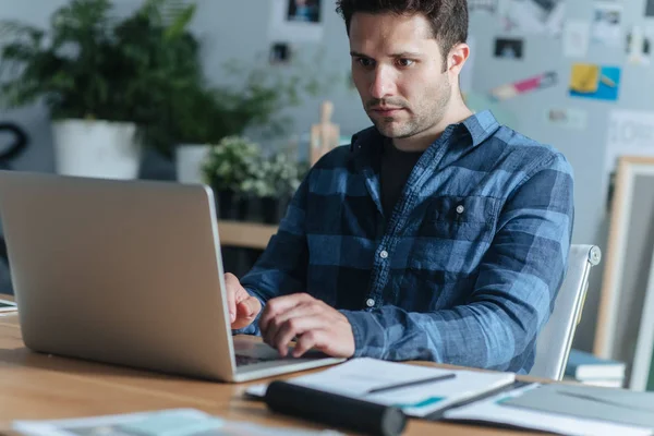 Modern ofis alanı bir dizüstü bilgisayar üzerinde çalışan yakışıklı genç beyaz iş adamı.