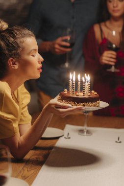 Güzel genç bayan doğum günü pastasında mum üflüyor..