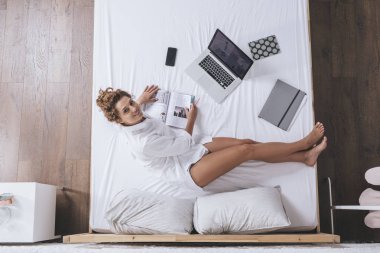 Onu laptop çalışma ve yatağın üstüne oturan kadın fotoğrafı yukarıda.
