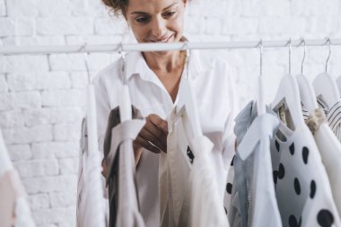 Giyecek kıyafet raf tarafından ayakta ve wath seçimi oldukça kafkas kadın.