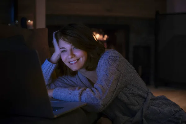 在家里看电影的漂亮微笑的女人在她的笔记本电脑 — 图库照片