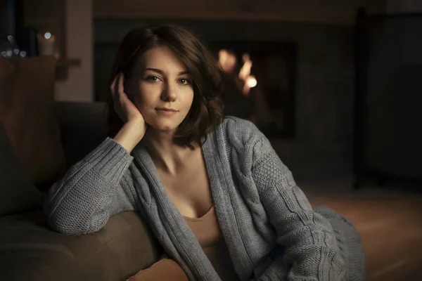 Beautiful Caucasian woman Sitting by the fireplace and looking at camera.