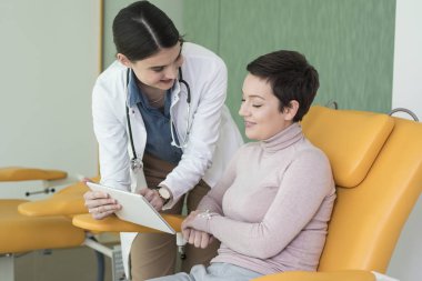 Kadın doktor ve onun hasta tablet vasıl birlikte arıyorsunuz.