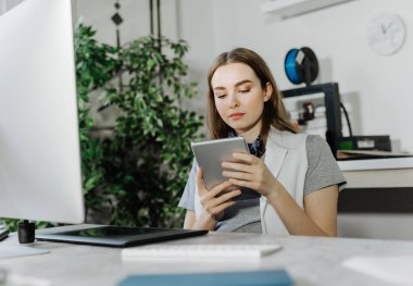 Office çok kafkas kadın grafik tasarımcı oturan ve tablet kullanma.