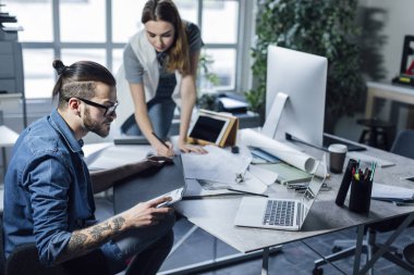 Genç erkek ve kadın tasarımcılar planları ile çalışma.