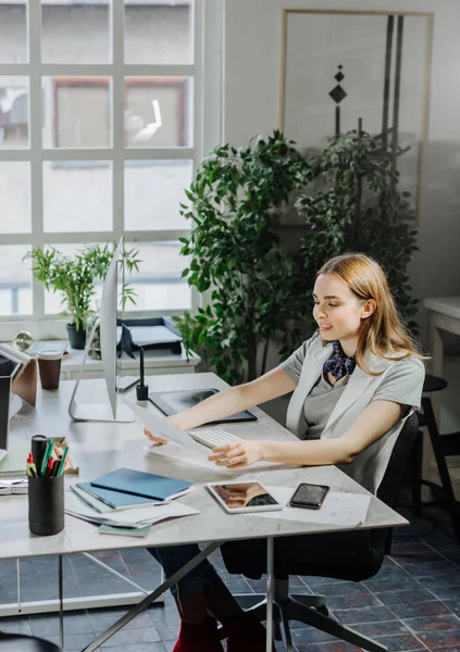 Pretty caucasian woman graphic designer sitting at office and looking at paper.